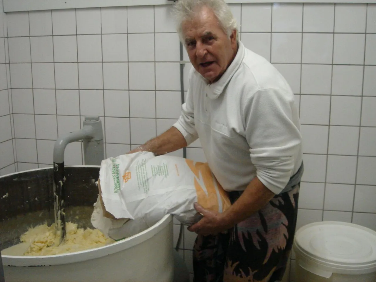 Meel wordt in de deegmachine gestort in de bakkerij